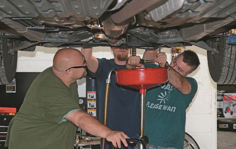 EHG clients receive instruction on how to change a car's oil