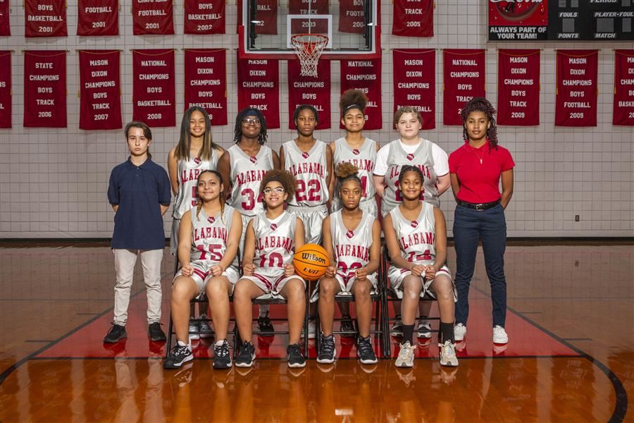 2021-22 ASD junior high girls basketball team members pose for the team photo in the gym.