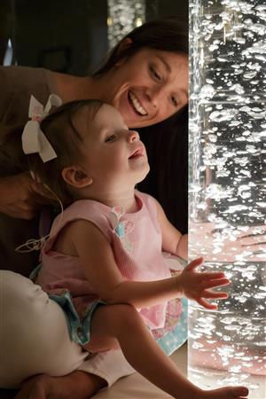 Mom with small child in her lap. Child is looking at bubbles.