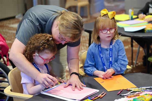 trainer Susie Thomas assists child with hand painting activity
