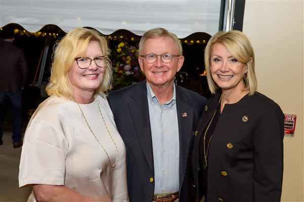 Two women and a man smile at the camera. 