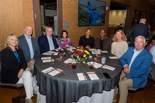 Eight people are seated around a table smiling at the camera.