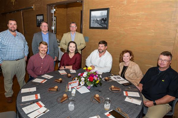 Three people stand and five people sit at a table. They all smile at the camera.