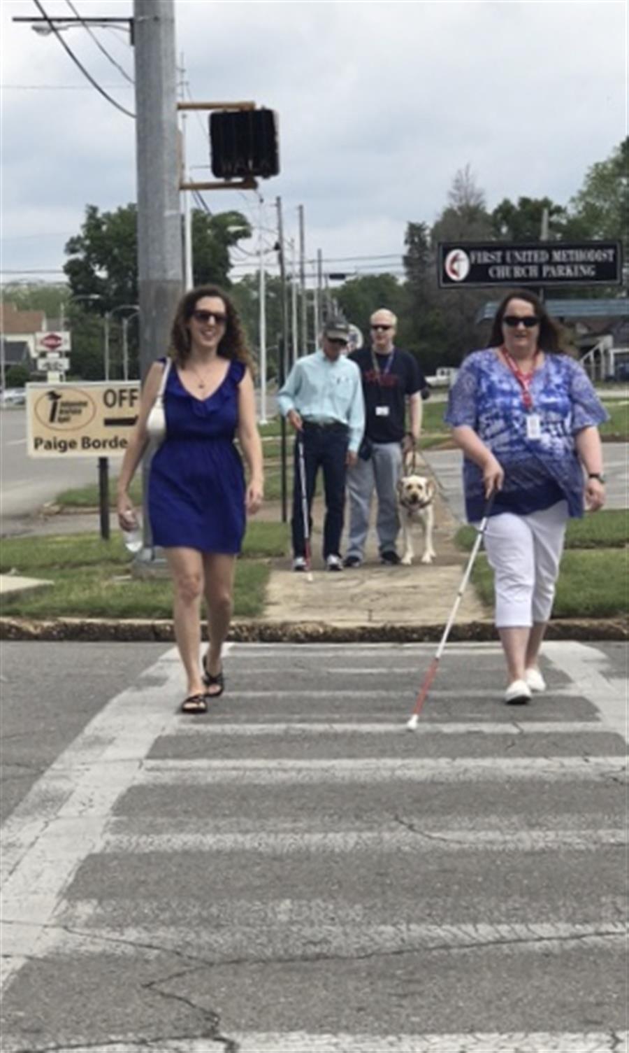 People crossing the street. Some use white canes. 